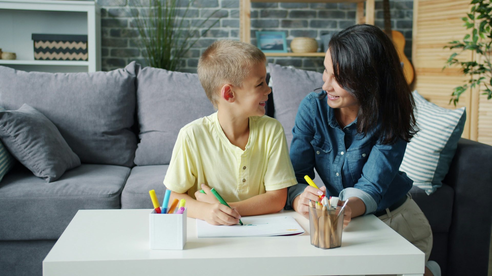 Une mère et son fils dessinent ensemble à une table.